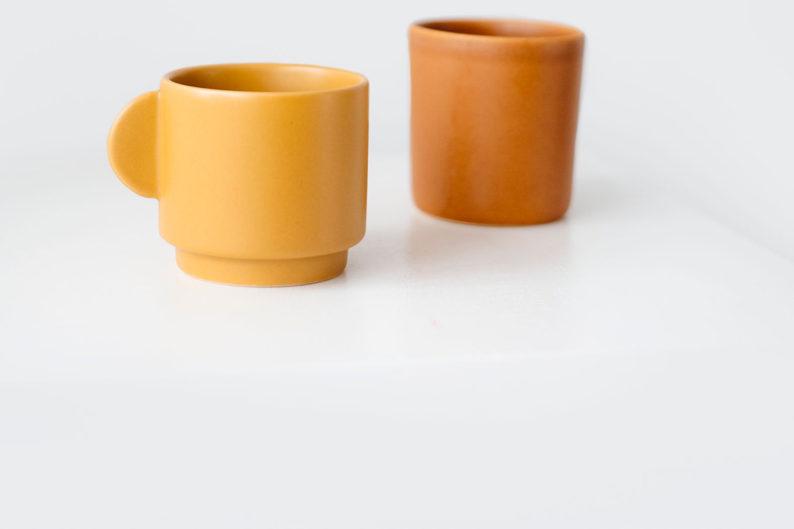 Two simple ceramic cups together on a pale surface